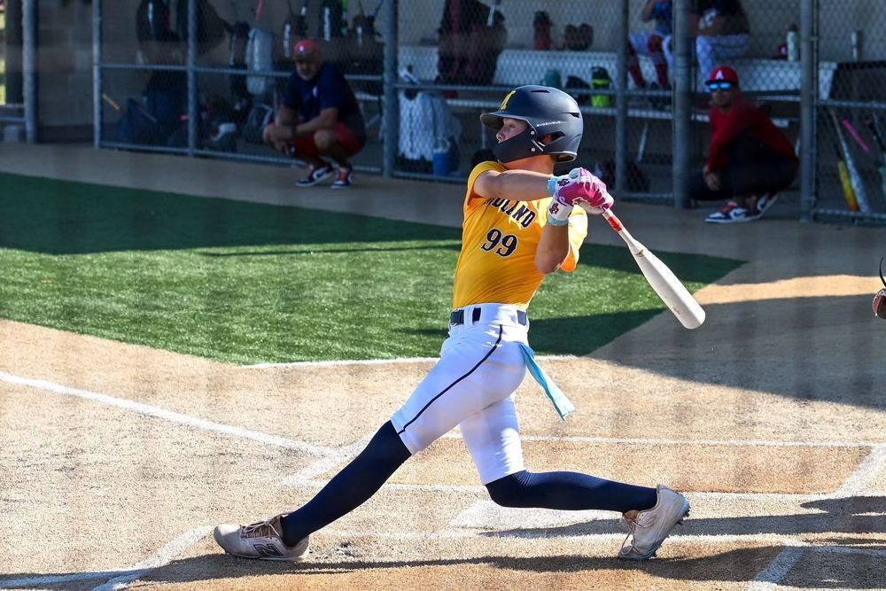Youth baseball player mid-swing wearing a number 99 jersey